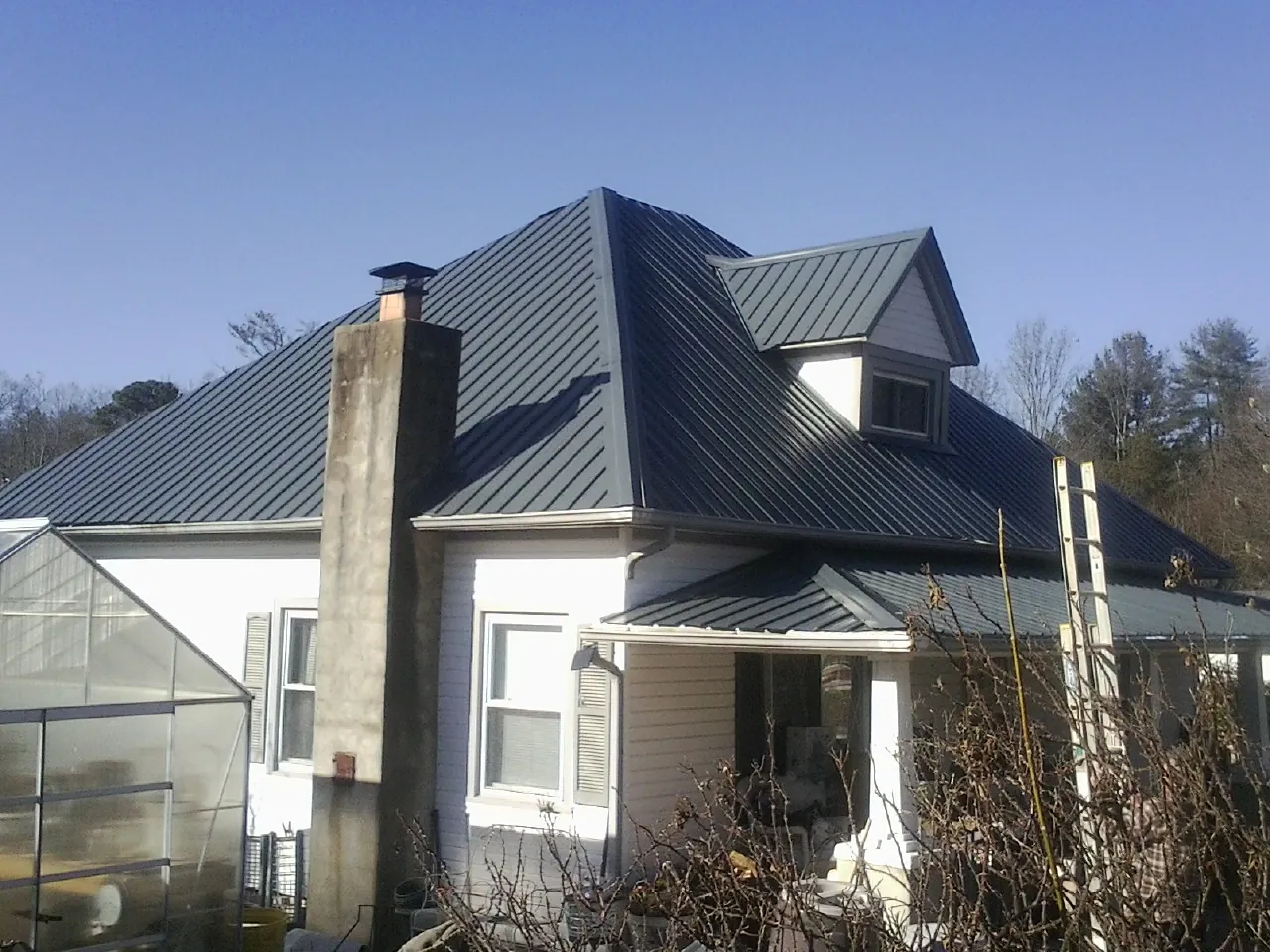 Dark blue standing seam metal roof on a white farmhouse with dormer — Slate & Tile Roof Repair by Roofing Brothers in Hudgins