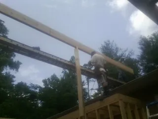 Carpenter setting a ridge beam over a new addition frame — Ice Dam Removal by Roofing Brothers in Hudgins