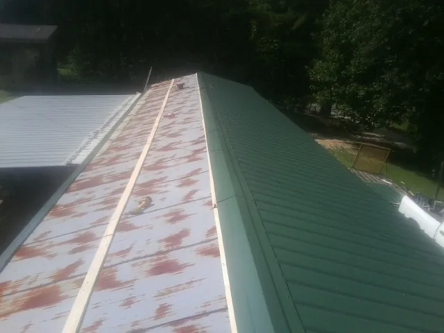 Old rusted panels beside newly installed green metal roofing — Wind Damage Roof Repair by Roofing Brothers in Hudgins