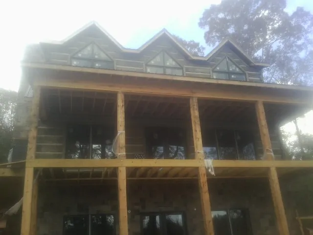 Dormers and porch framing on a large log home under construction — Roof Coating work by our crew in Hudgins