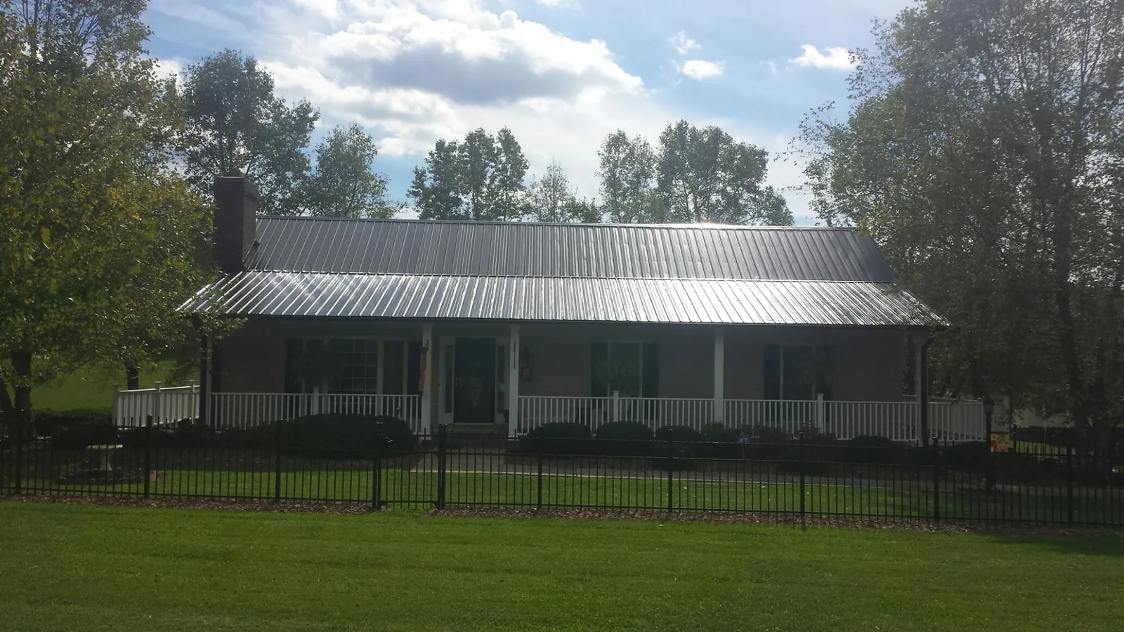Gray metal roof on a brick ranch with a full width front porch — Gutter Guard Installation work by our crew in Hudgins