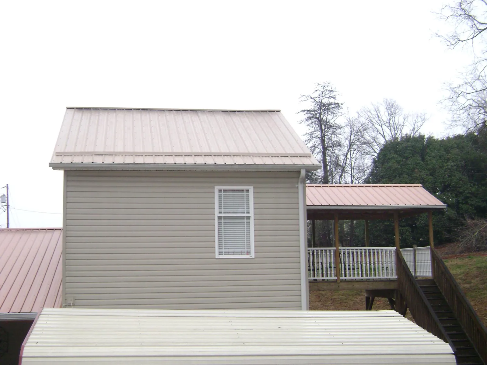 Tan metal roofs on a two story addition and attached porch, from a Roof Replacement job in Hudgins