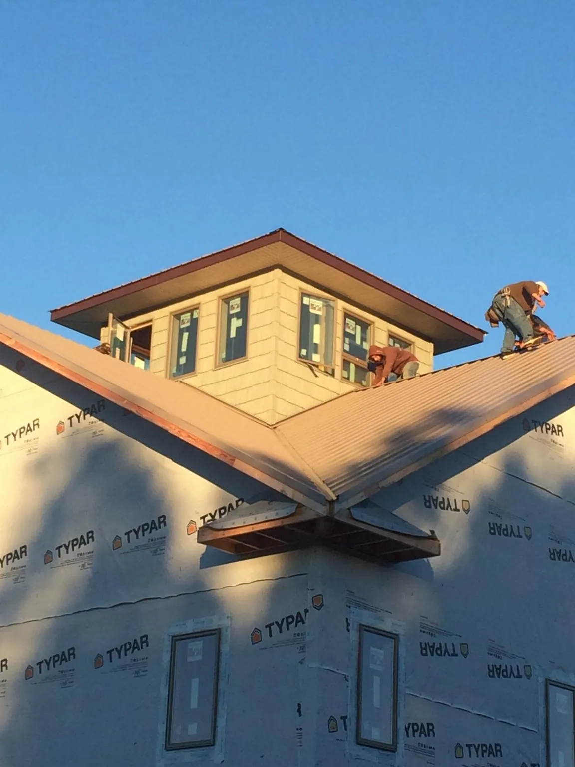 Roofers working around a rooftop cupola on a new metal roof at sunset — Roof Waterproofing in Hudgins by Roofing Brothers